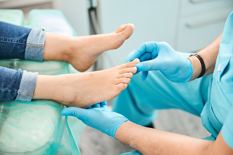 Podiatrist examining a patient's toe during evaluation and treatment of common toenail conditions.