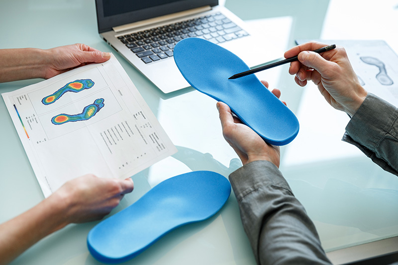 Healthcare professional reviewing custom orthotics and foot pressure mapping results with a patient.