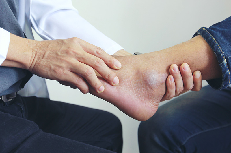 Podiatrist evaluating a patient's foot and ankle condition during a comprehensive examination.