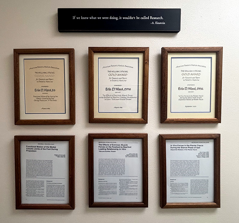 dr-erin-ward-awards Six framed certificates and research publications displayed on an office wall honoring Dr. Erin Ward's research achievements.