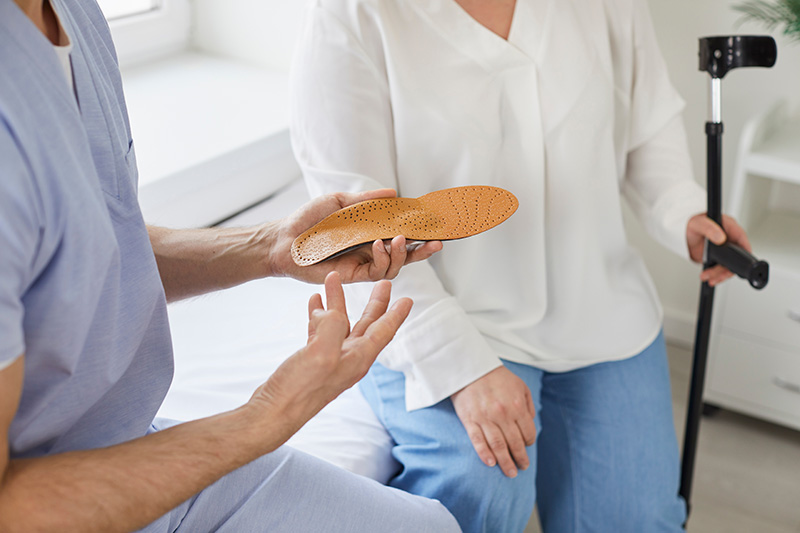 podiatrist-patient-orthotic-insoles Patient consulting with a podiatrist about custom orthotics for foot pain and improved mobility.